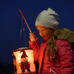 Portrait of little girl with lighted paper lantern on St. Martin's Day at twilight